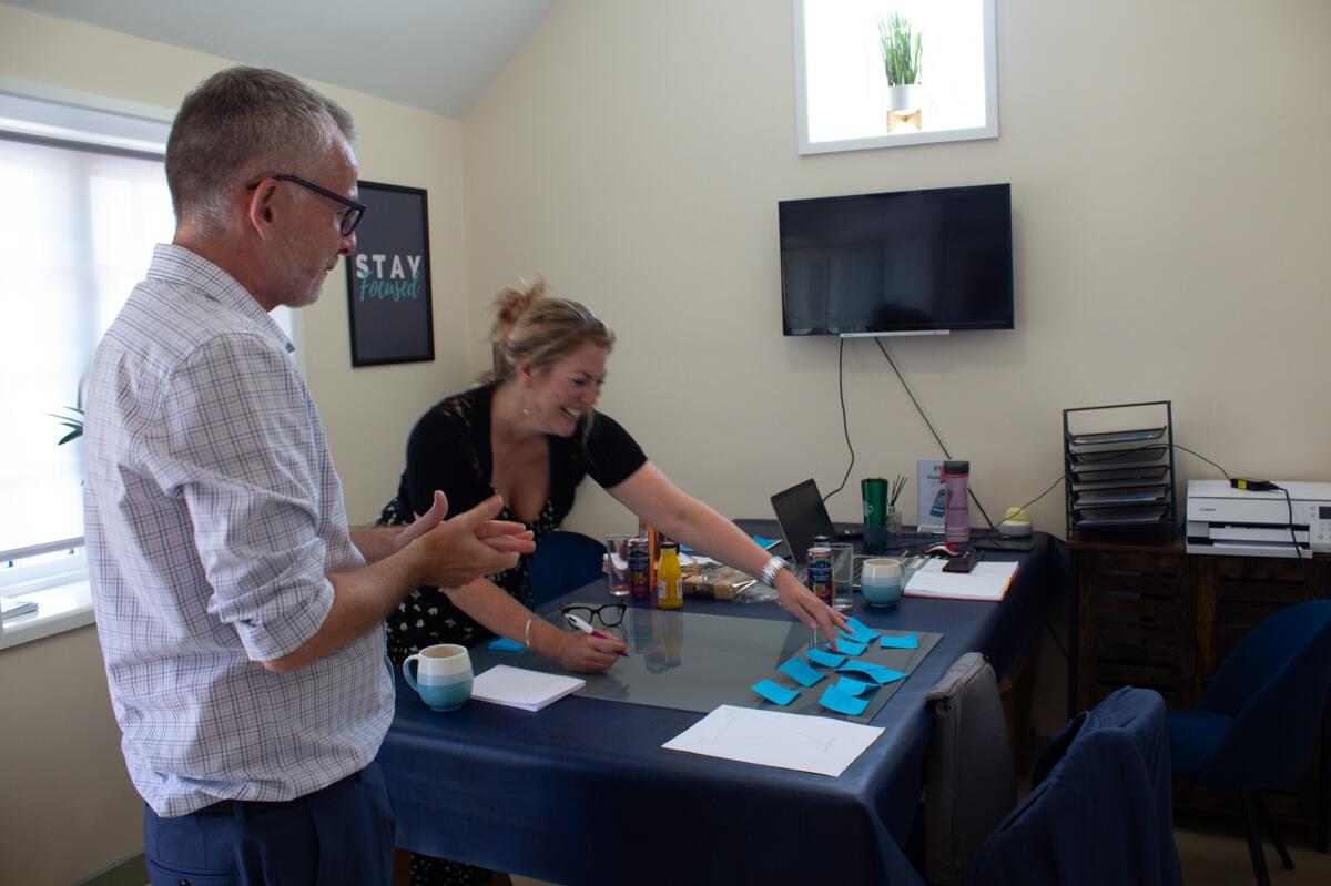 Two people laughing while working through a strategy session with sticky notes