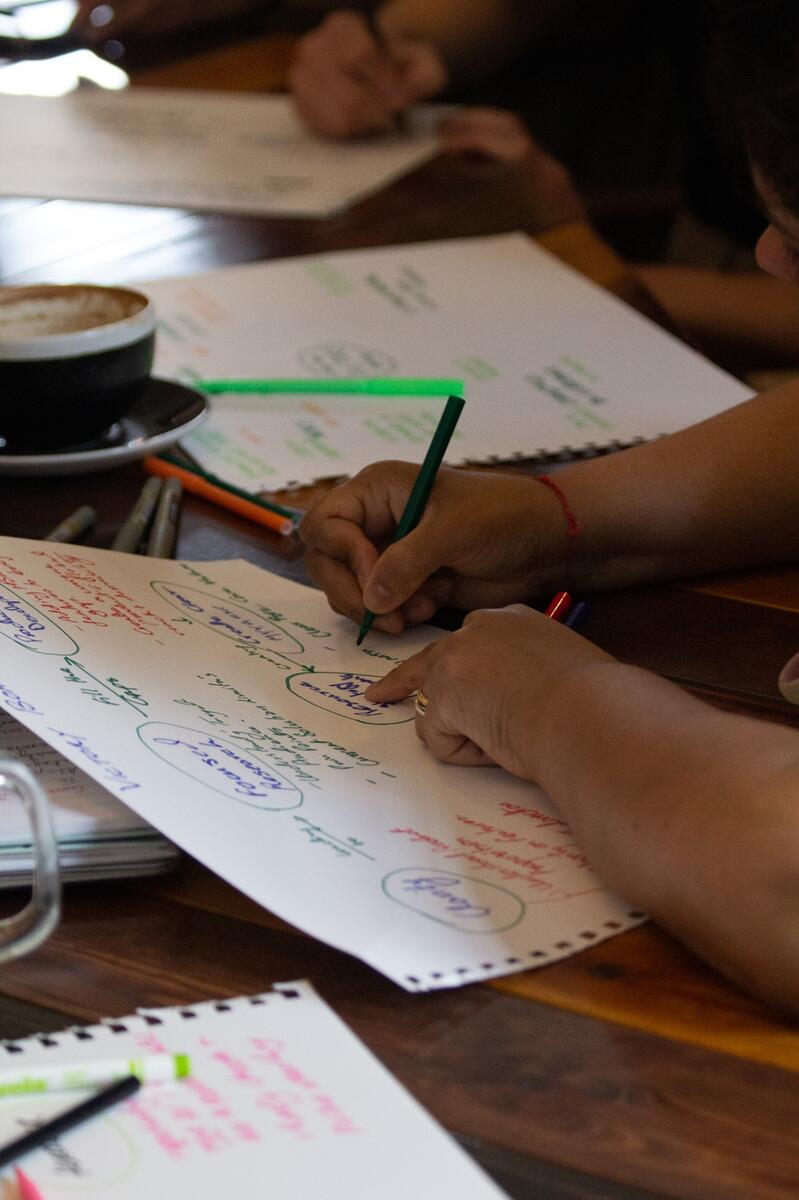 Hands sketching a growth strategy flowchart in a notebook beside a coffee cup