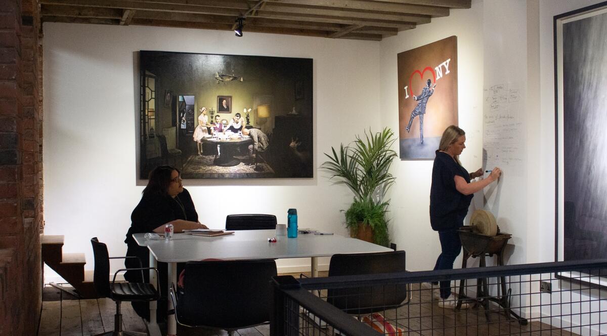 A coach writing a plan on the wall while a business owner looks on